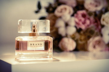 Perfume bottle on table and flowers at background. Aromatic Eau de Toilette