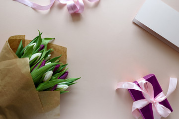 Bouquet of white and purple tulips, gift box and blank paper on pink background. Top view. Flat lay. Copy space. Valentines day, mothers day, birthday, wedding celebration concept.