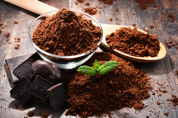 Composition with bowl of cocoa powder on wooden table