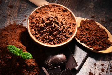 Composition with bowl of cocoa powder on wooden table