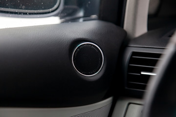 Modern round speaker in black color on the door inside the car interior, circle dynamics with...