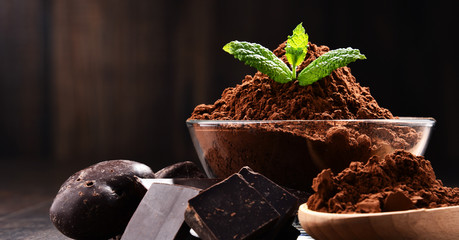 Composition with bowl of cocoa powder on wooden table