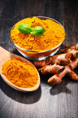 Composition with bowl of turmeric powder on wooden table