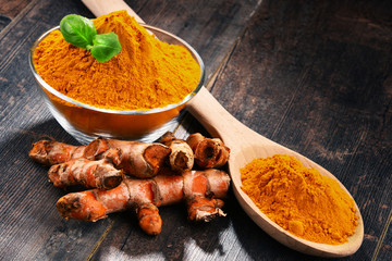Composition with bowl of turmeric powder on wooden table
