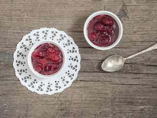 Homemade strawberry sweet tasty jam with whole berries on wooden background. Top view