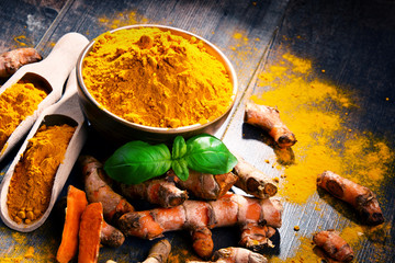 Composition with bowl of turmeric powder on wooden table