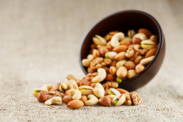 Walnut platter spilled out of the cup on the background of cloth from burlap. Nuts as structure and background, macro.