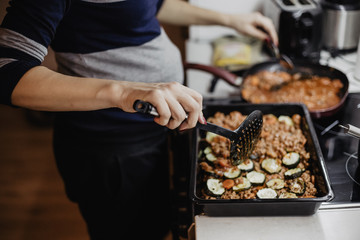 Woman in the kitchen preparing a moussaka on the stove