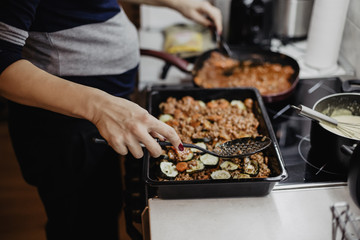 Woman in the kitchen preparing a moussaka on the stove