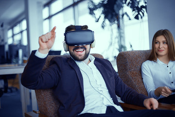 Adult bearded man with virtual reality vr glasses with woman at office
