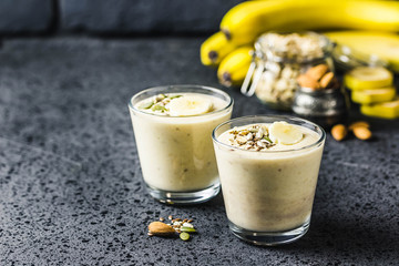 Oats banana almond milk shake with nuts and seeds on dark background. Selective focus, space for text.