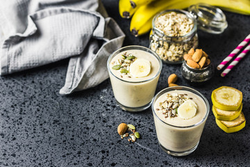 Oats banana almond milk shake with nuts and seeds on dark background. Selective focus, space for text.