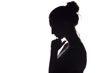 profile silhouette of a sad girl with a hand at the chin, a young woman lowered her head and praying to God