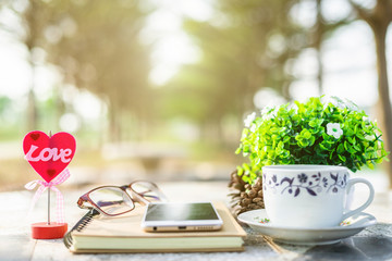 Close-up of empty notebook,smartphone,spectacles and cup of coffee on Marble floor background. Love concept with heart desktop,Valentine's Day.