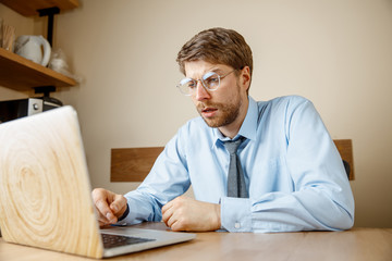 Fototapeta premium Feeling sick and tired. Frustrated sad unhappy sick young man sitting at his working place in office. The seasonal flu, pandemic influenza, disease prevention concept