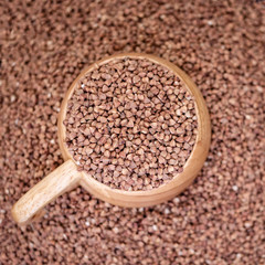 Wooden cup brim full of buckwheat, a soft background cereals. Close-up.