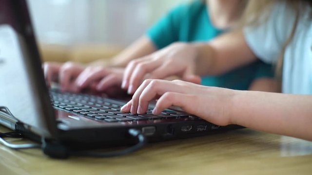 closeup of children hands playing online computer games on laptop