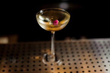 Elegant glass filled with tasty sweet cocktail decorated with rose bud