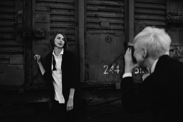 two woman in classic costumes shooting each other at moment camera at railway station at the sunset