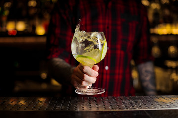 Bartender holding a glass of fresh sour and sweet citrus cocktail