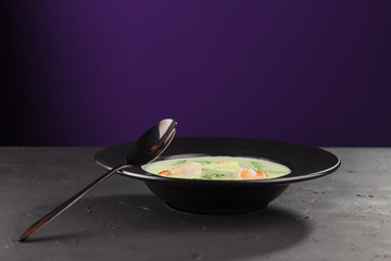 Cream broccoli soup with shrimp in a beautiful black plate on a dark background. Seafood dish. Selective focus.