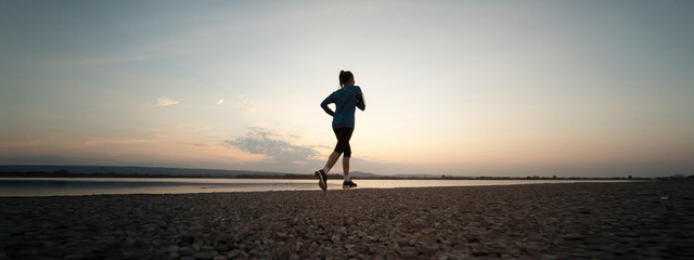 Woman running with sunset or sunrise background