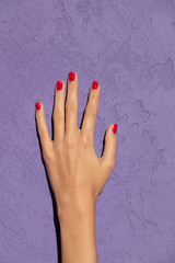 Hands with red nails on magenta background