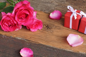 Elegant pink rose, gift box decorated with petals and card with natural soft light on wood background, beautiful valentine's day background concept