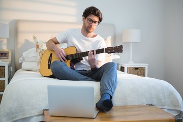 Man playing guitar in bedroom