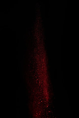  red powder in air and falling down on black background