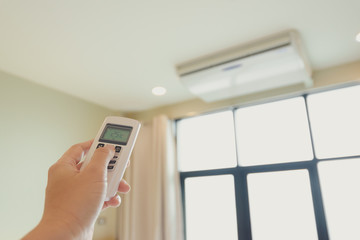 Fototapeta premium One man's hand is pressing the air conditioner remote in his hand to rest..&nbsp;.