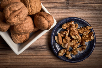 group of tasty nuts next to a bowl on an old wooden board
