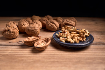 group of tasty nuts next to a bowl on an old wooden board
