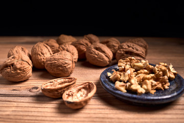 group of tasty nuts next to a bowl on an old wooden board
