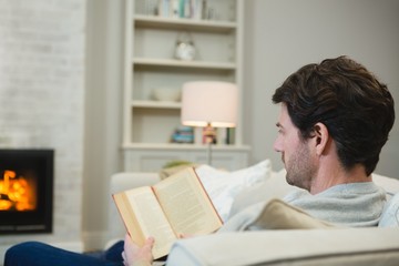Obraz premium Man reading a book in living room
