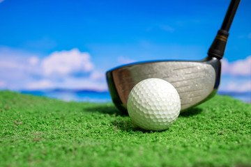 Golf club and golf ball on tee in grass