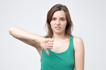 Pretty woman in green csummer clothes showing thumbs down