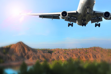 Fototapeta na wymiar plane flies in the blue sky against the backdrop of a mountain landscape, flies away