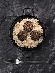 vertical shot of stewed rice with blood sausage on a dark marbled background