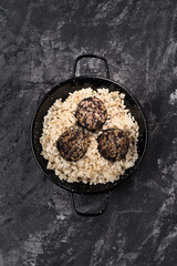 vertical shot of stewed rice with blood sausage on a dark marbled background