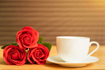Fototapeta na wymiar Red rose and coffee cup on wood