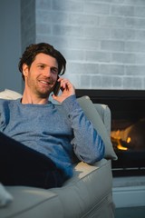 Fototapeta premium Mężczyzna rozmawia przez telefon komórkowy w salonie