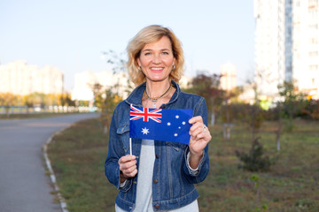 Mature woman with Australia flag on city and blue sky background.