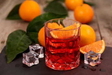 A glass of Negroni cocktail with Campari, Vermouth, Gin and Oranges. Alcoholic drink on dark stone...