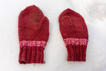 handmade red mittens on white snow
