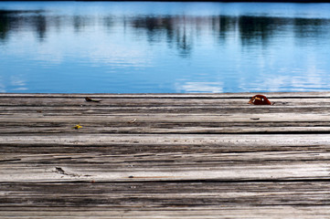 Low angle view of old wooden pier or dock looking out over water with reflections.