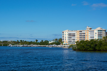 Scenic view of Bonita Springs Florida, looking across canal towards large building and boat docks.