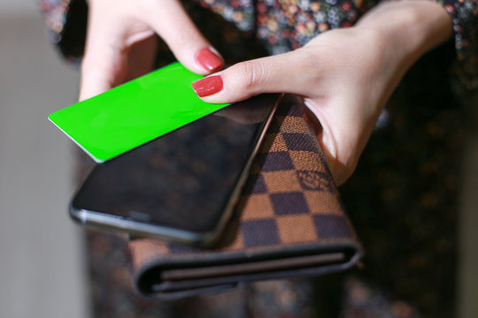 Woman holds wallet, phone and card. Card is empty green for your logo