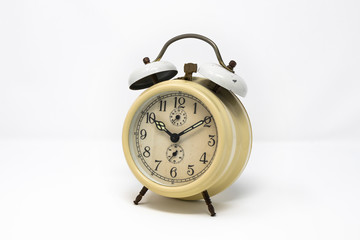 old yellow analog twin bell alarm clock isolated on a white background. Vintage metal object, ruined by time. Wake up early in the morning to the sound of the bell.