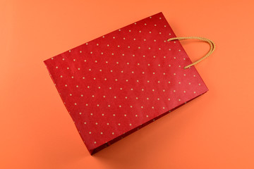 Red packet with polka dots on an orange background. Copy space.